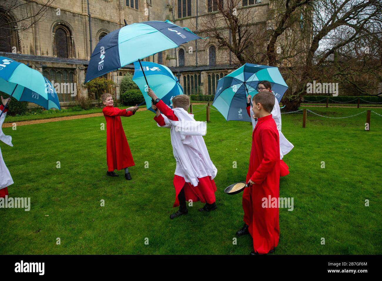 Das Bild vom 24. Februar zeigt den Chor der Ely-Kathedrale in Cambridgeshire, nachdem er am Dienstag im Regen für tomorrowÕs Pancake-Rennen geübt hat. Das regnerische Wetter didnÕt hält Chorherren in der Ely Cathedral in Cambridgeshire davon ab, heute Morgen (Mo) für ihr jährliches Pfannkuchenrennen zu üben. Die Jungen und Mädchen, die ihre roten und weißen Socken trugen, hielten Regenschirme, als sie Pfannkuchen vor der beeindruckenden Kathedrale aus dem 12. Jahrhundert umkippten. Die Jugendlichen lachten und kicherten, als sie für tomorrowÕs traditionelle Veranstaltung probten und bekamen trotzdem ihre Pfannkuchen, die ihre Fähigkeiten warfen, in den Griff Stockfoto