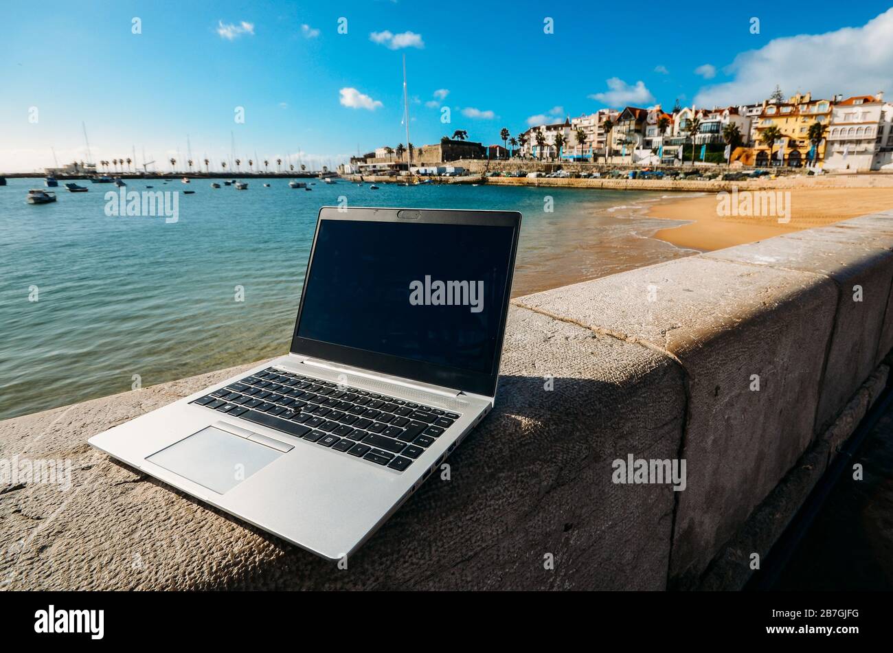 Generisches Notebook Laptop am sonnigen, einsamen sandigen Strand im Hintergrund. Paradise Home Office Konzept speziell bei Coronavirus Covid-19 Ausbruch Stockfoto