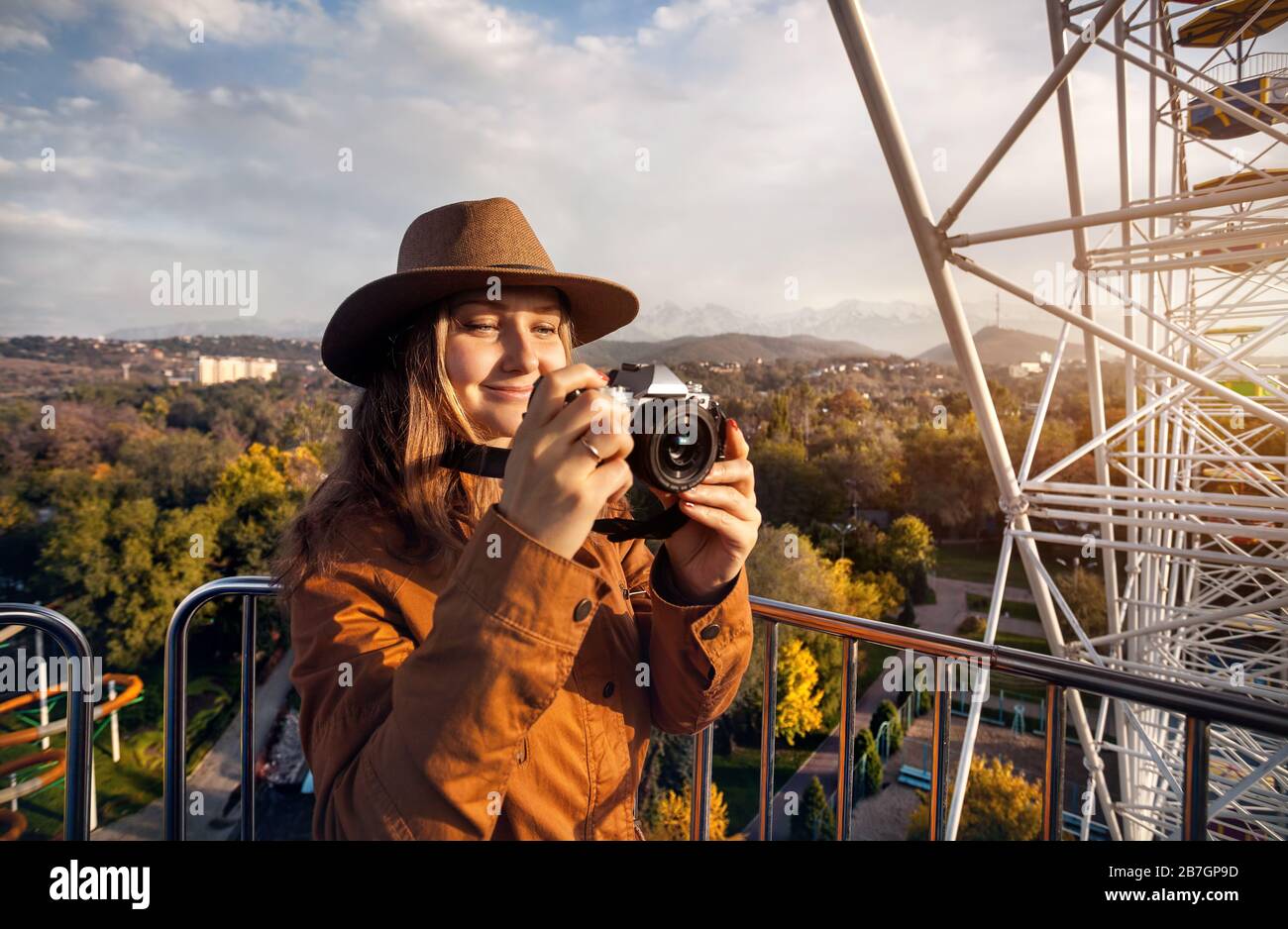 Frau unter Bild mit Vintage-Kamera in der Hütte des Riesenrads im Herbst Park bei Sonnenuntergang Stockfoto