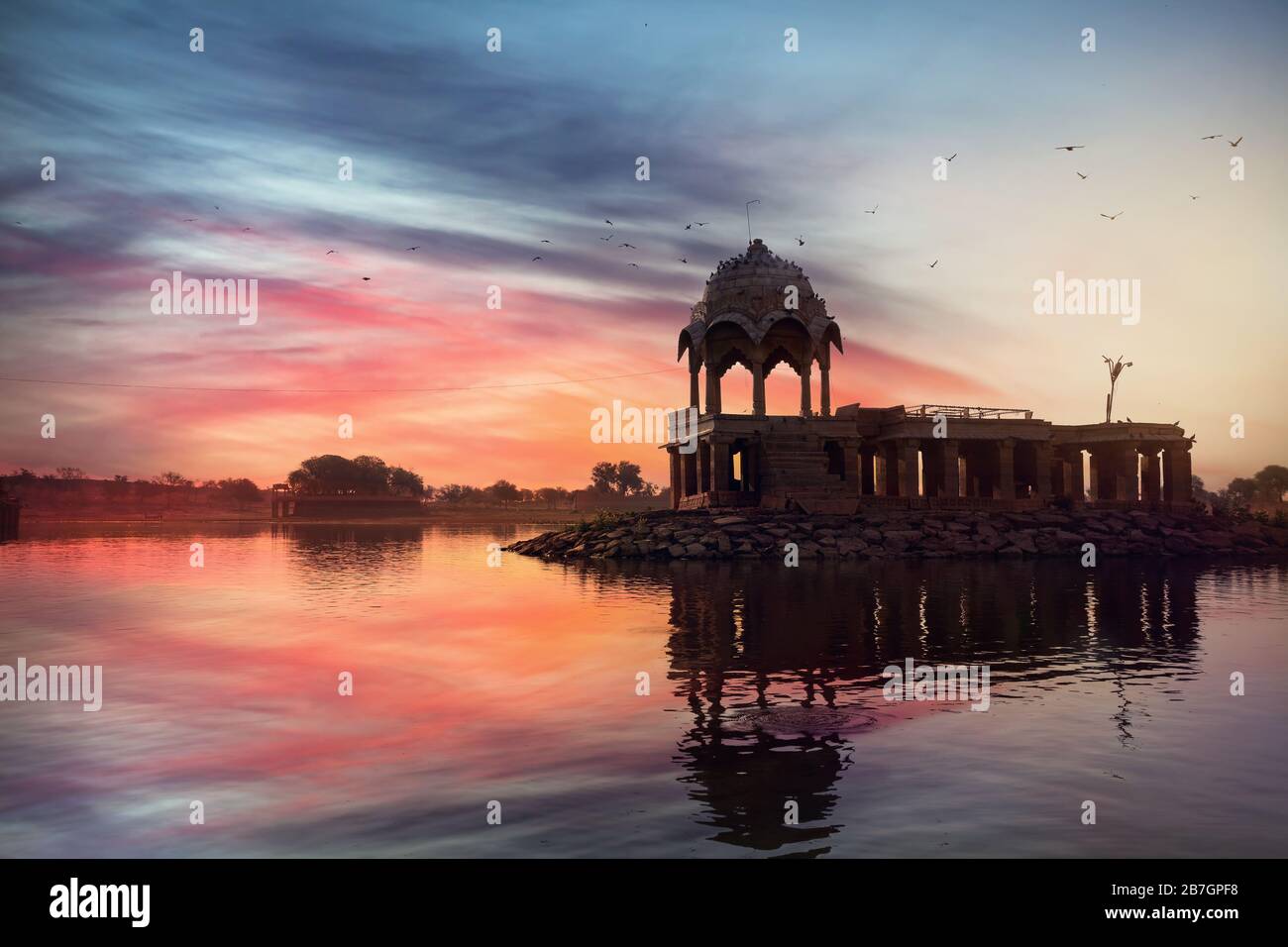 Silhouette des Tempels auf dem Gadi Sagar See in rosa lebendige Sonnenuntergang Himmel in Jaisalmer, Rajasthan, Indien Stockfoto