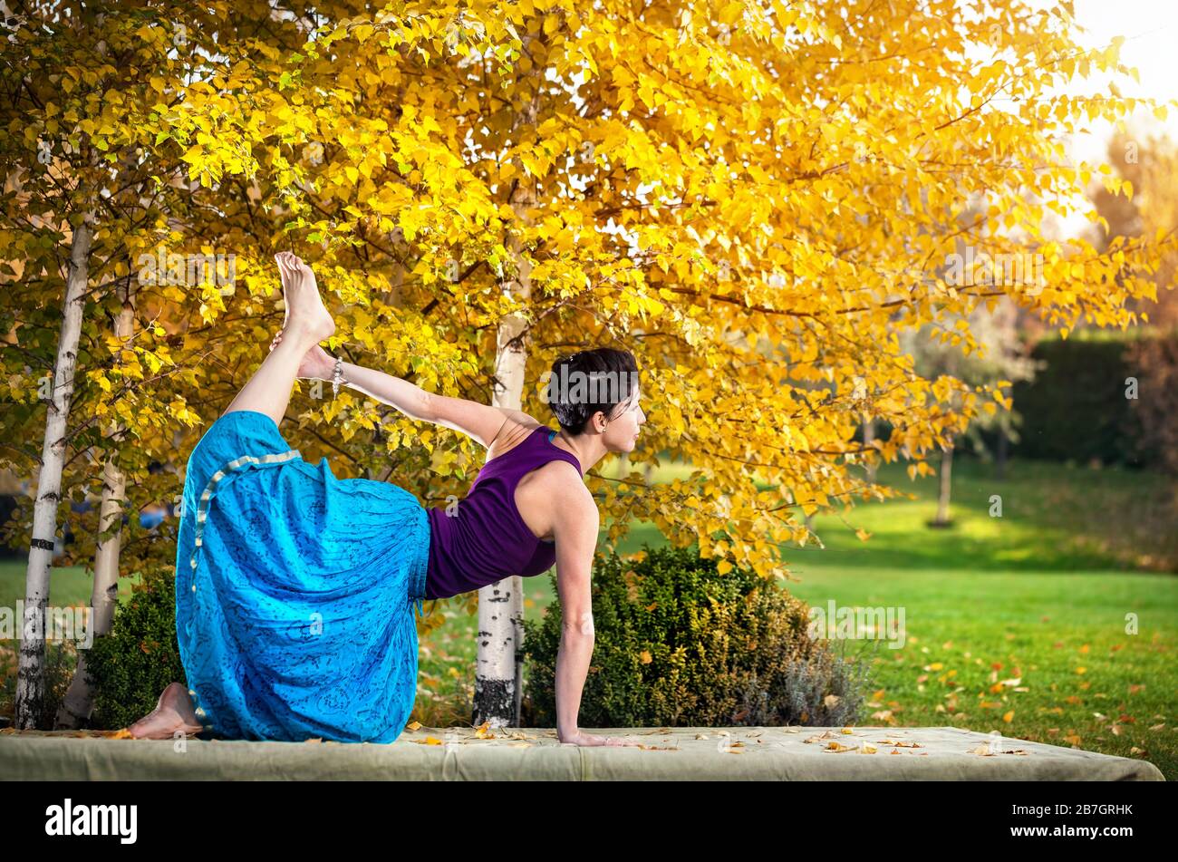 Junge Frau beim Yoga im Herbst Stadtpark in der Nähe von Birken gelb Stockfoto