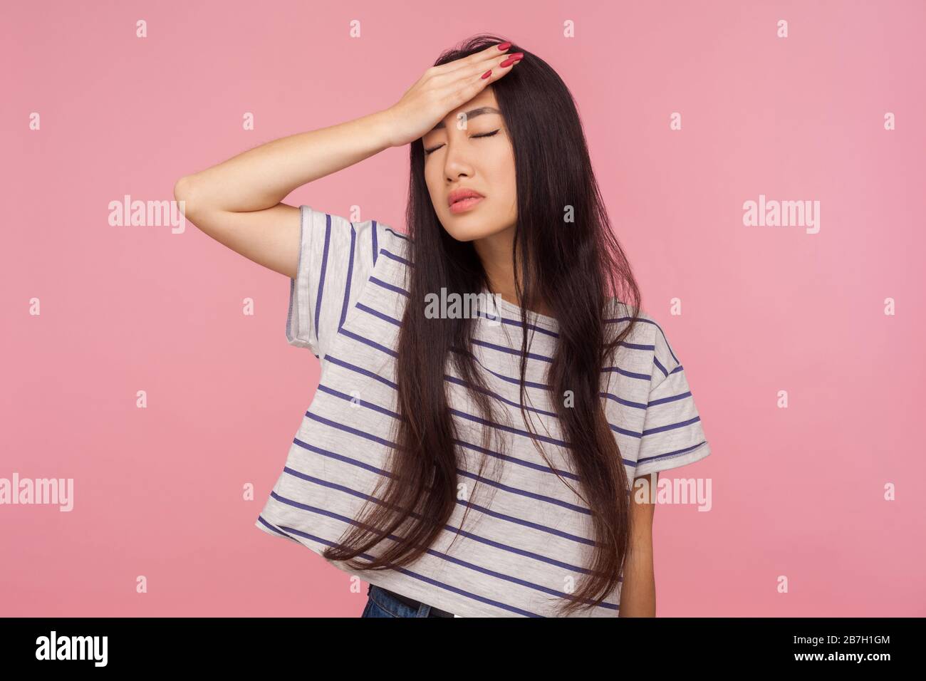 Facepalm. Porträt des bedauerlichen Mädchens mit brünettem Haar im gestreiften T-Shirt, das die Hand auf die Stirn legt, Trauer und Verzweiflung über Verlust, Misserfolg verspürt. Stockfoto