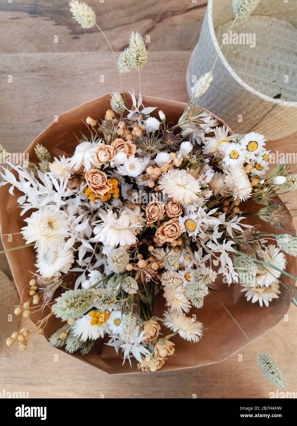 Getrocknete Blumenarrangement für eine Hochzeit in neutralen weichen Beige- und Weißtönen auf Holzhintergrund Stockfoto