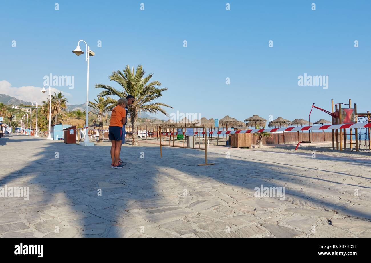 Urlauber lesen eine lokale Polizei, die vor einer Schließung des Strandes wegen der sozialen Distanzierungsmaßnahmen von Coronavirus warnt, Nerja, Málaga, Spanien Stockfoto