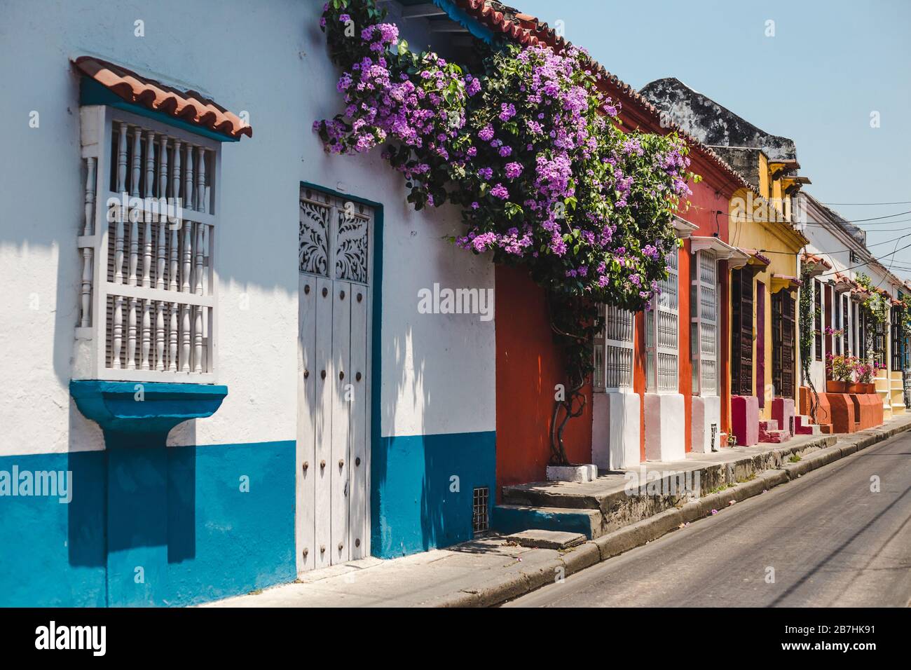 Typische farbenfroh bemalte Wohnstraße, die in Cartagena de Indias, Kolumbien, mit Blumen bedeckt ist Stockfoto