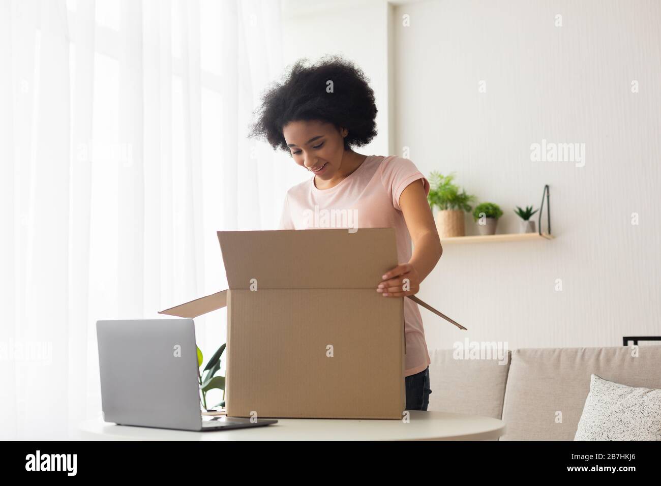 Überraschte amerikanerin mit Laptop öffnet Box Stockfoto