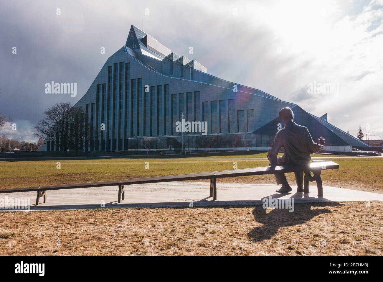 Eine Skulptur eines kleinen und großen Mannes auf einem Sitz - ein Stück über die Perspektive - vor der lettischen Nationalbibliothek in Riga, Lettland Stockfoto