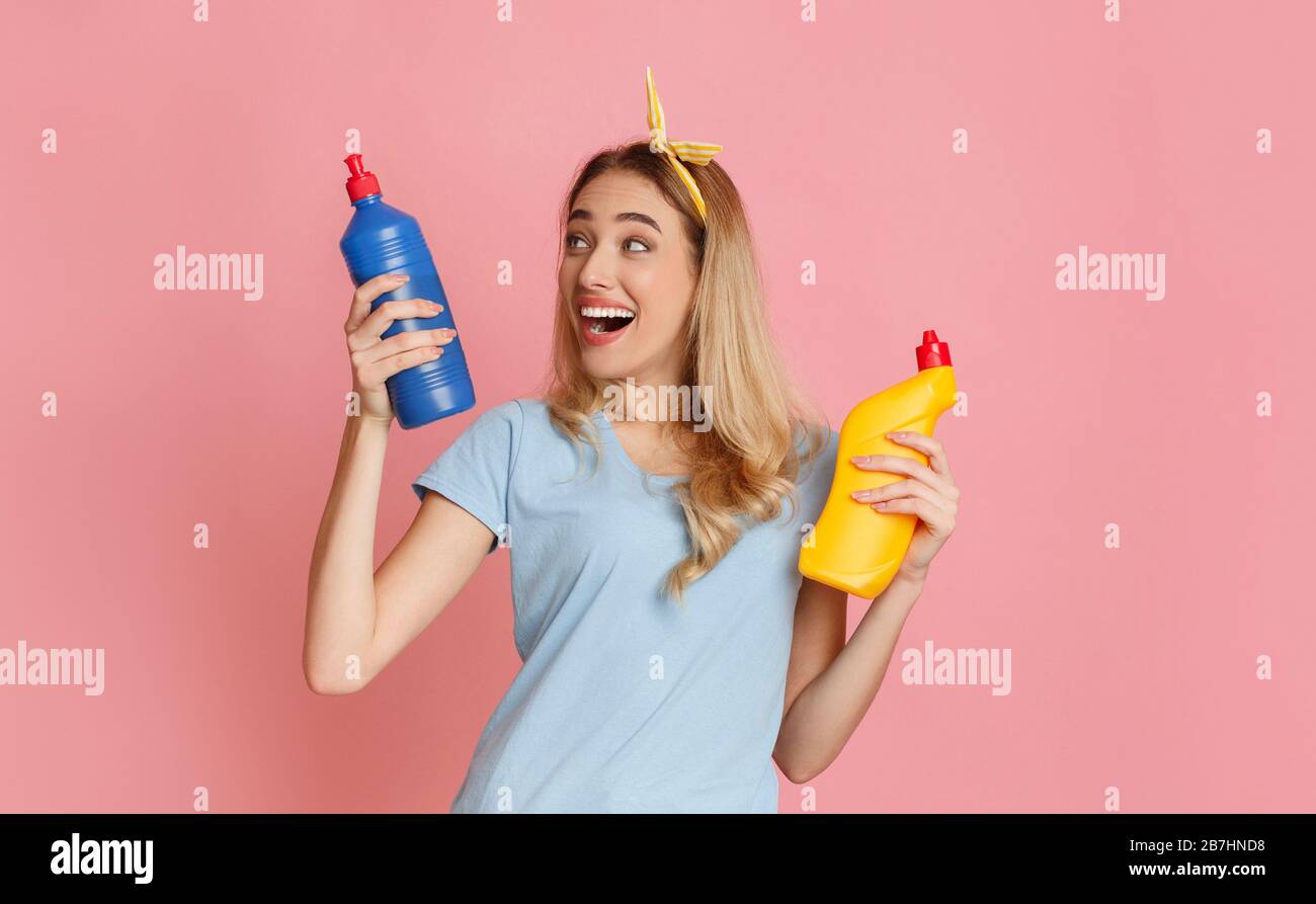 Das lachende Mädchen wählt eine Flasche Reinigungsmittel Stockfoto