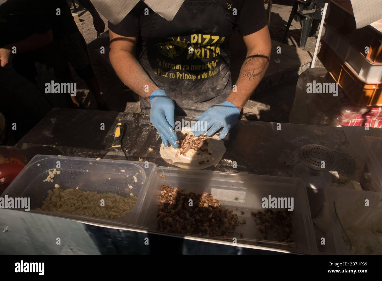 Ein Pizzakoch, der Teig mit Käse und Fleisch zur Zubereitung von Pizza aus dem Bratpfanne betäubt Stockfoto