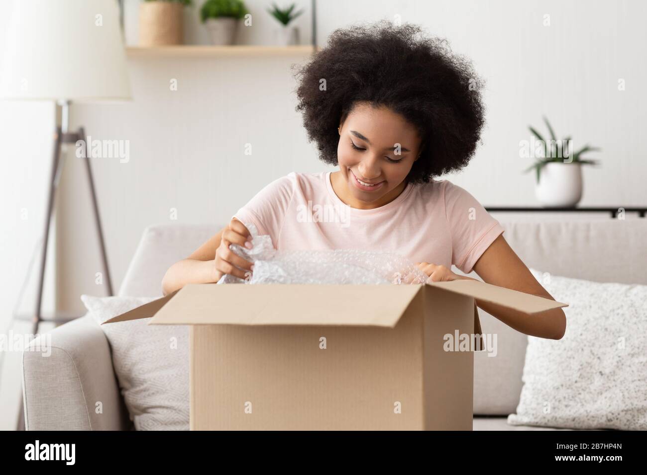 Kunden afroamerikanischer Mädchen packt eine Schachtel aus Stockfoto