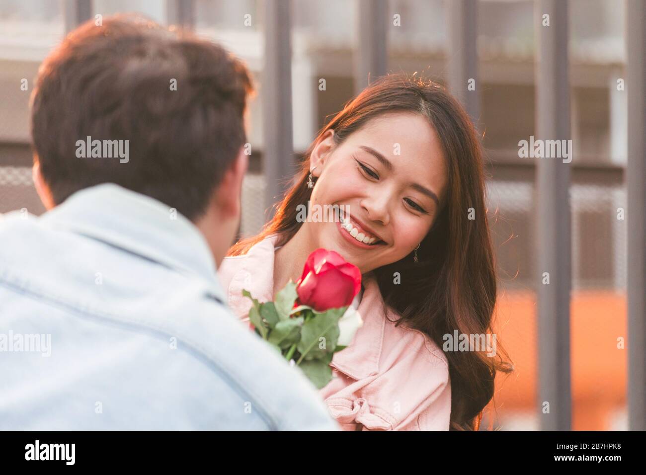 Junge glückliche Paare lieben und romantisch auf den ersten Tag Beziehung: asiatische Teenager-Frau überrascht und lächelt an Freund gibt rote Rosen-Blumen auf Dinne Stockfoto