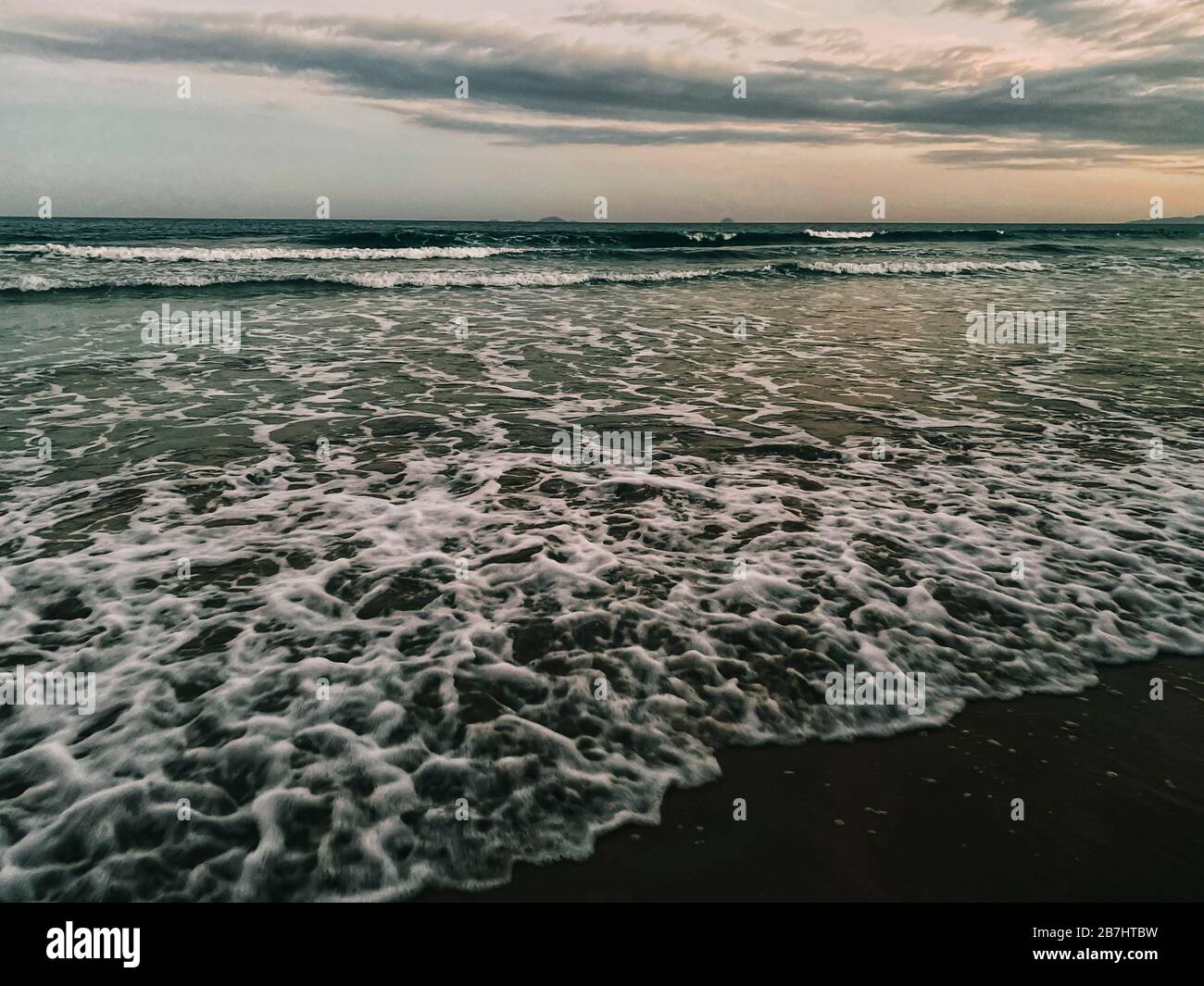 Sommer Meer Sonnenuntergang auf dem Cave Strand, Sonne, Wellen und Wolken, schöne dramatische Beleuchtung, Sonne hinter Stockfoto