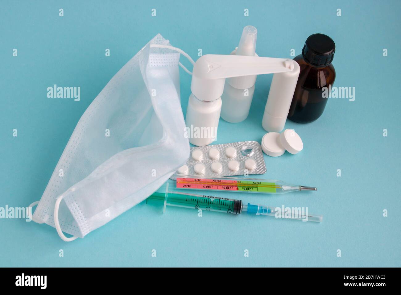 Medizinische Maske, Pillen und Spray für die Behandlung der Kehle auf blauem Hintergrund, das Konzept des coron-virus und der Gesundheitsversorgung. Stockfoto