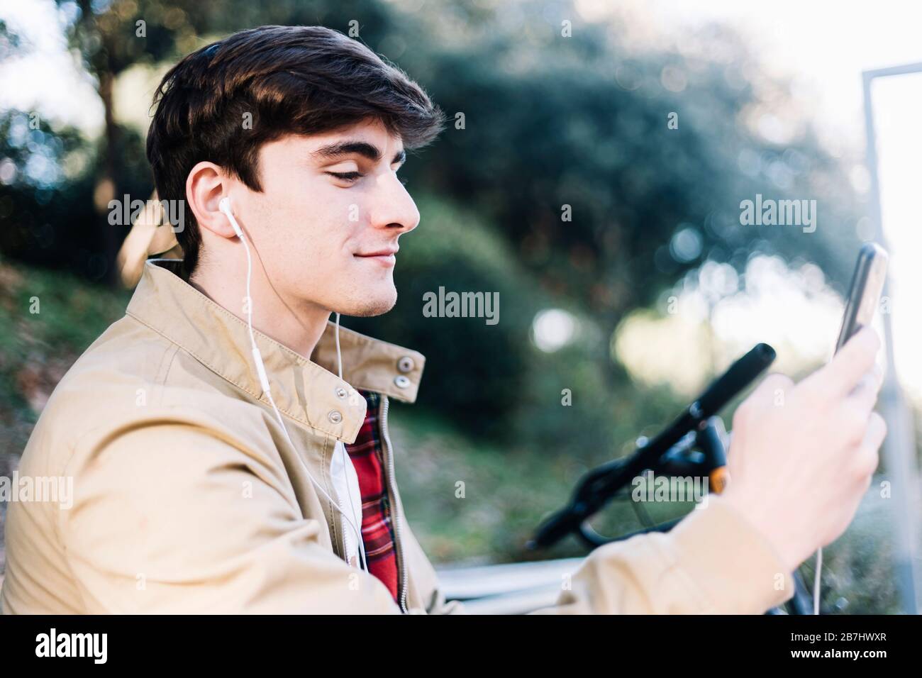 Junger Mann, der im Freien mit dem Handy sitzt Stockfoto