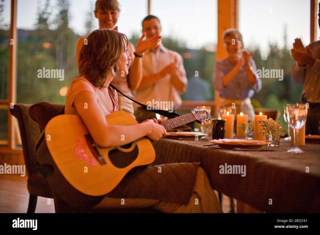 Familie klatscht nach einem Auftritt an der Gitarre am Esstisch für Frau ein Stockfoto