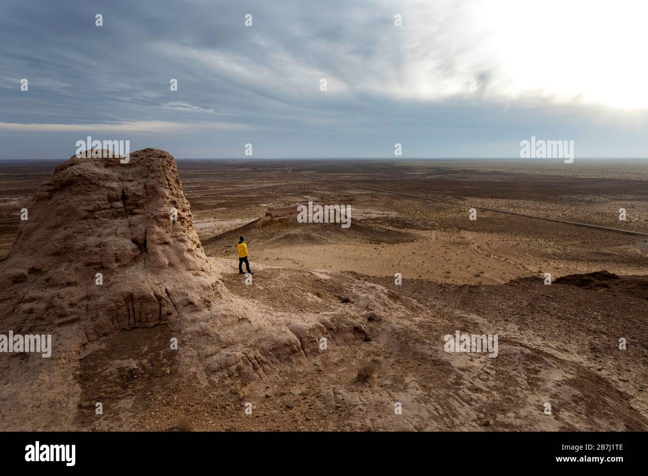 Frau, die sich auf den Ruinen der archäologischen Stätte Ayaz-Kala auf einem Hügel mit Blick auf die Wüste Kyzylkum, Karakalpakstan, Usbekistan, befindet Stockfoto