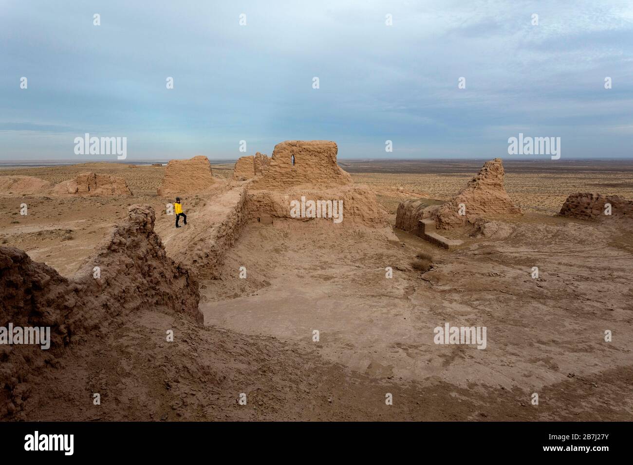 Frau, die in den Ruinen der archäologischen Ausgrabungsstätte Ayaz-Kala auf einem Hügel mit Blick auf die Wüste Kyzylkum, Karakalpakstan, Usbekistan, steht Stockfoto