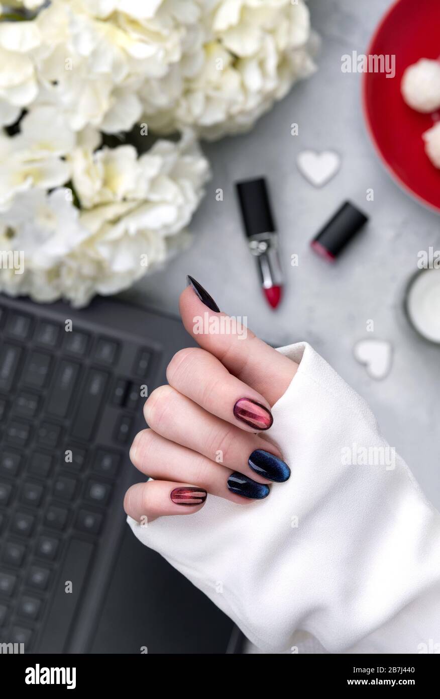 Schöne gepflegte Damenhände mit dunklem Glitter, polnischem Nageldesign Stockfoto