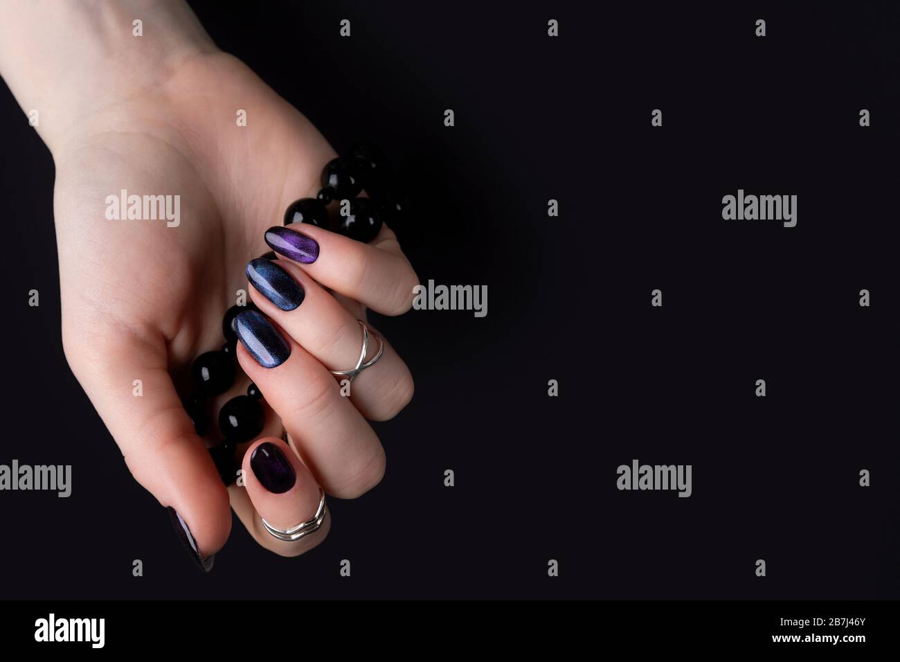 Schöne gepflegte Damenhände mit dunklem glitzernden, polnischem Design auf Nägeln Stockfoto
