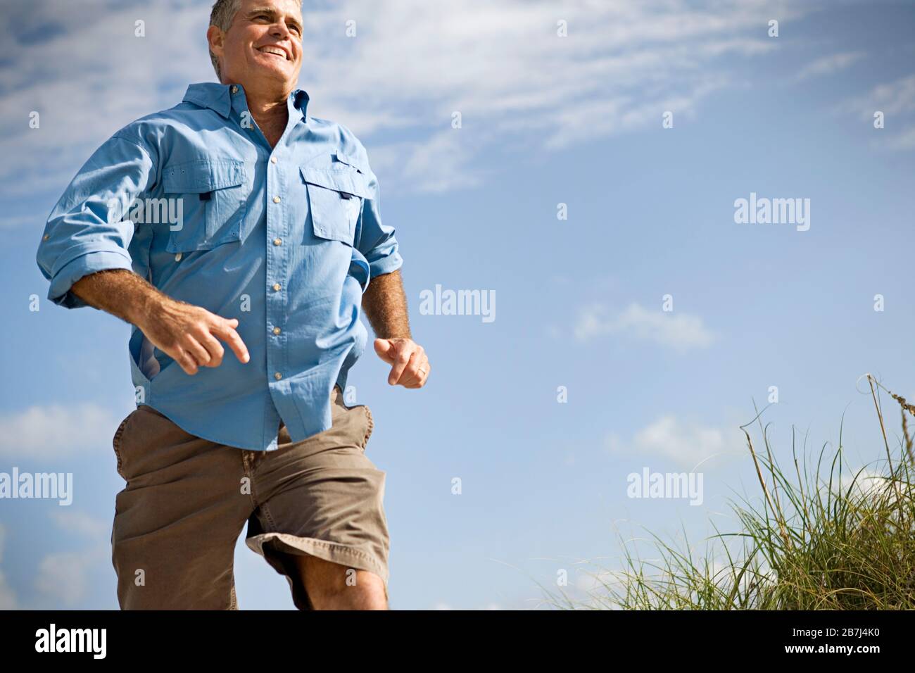 Reifer Erwachsener, der durch Gras läuft. Stockfoto