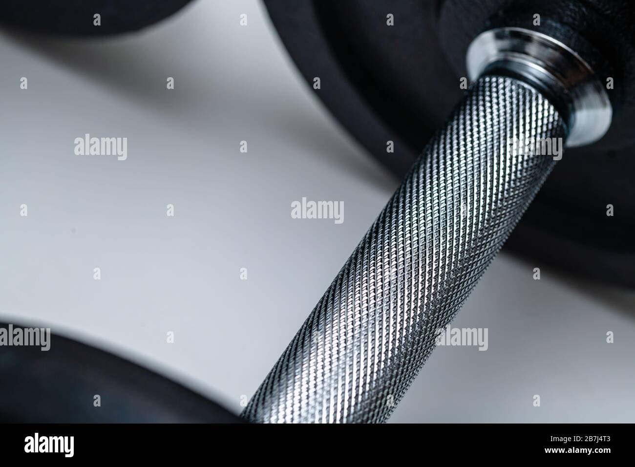Nahaufnahme des verstellbaren Hantelgriffs mit aufgesetzten Gewichten auf weißem Hintergrund. Konzept von Training, Fitness und Bewegung für ein gesundes Leben. Stockfoto