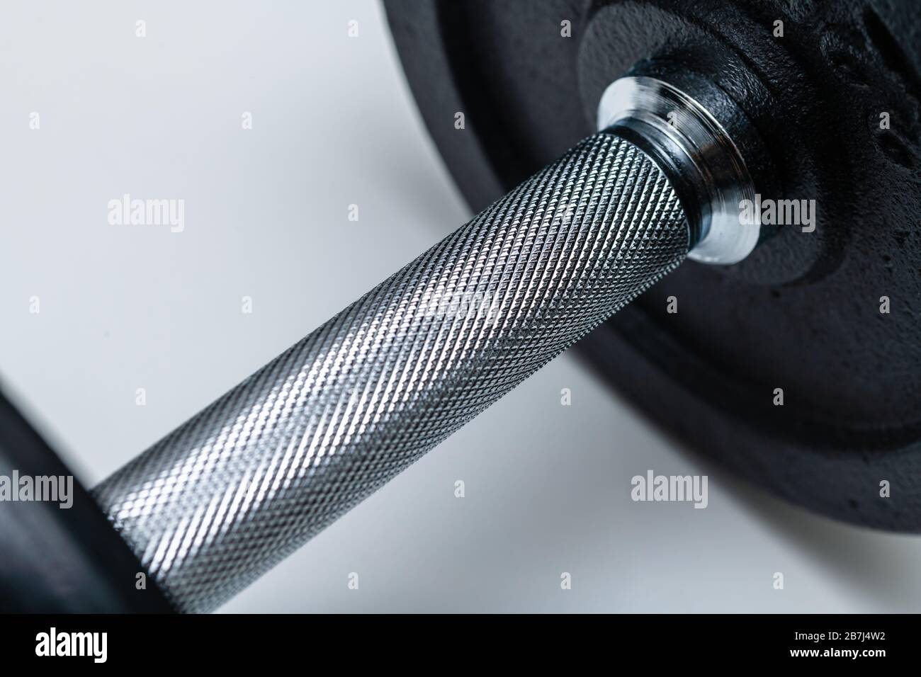 Nahaufnahme des verstellbaren Hantelgriffs mit aufgesetzten Gewichten auf weißem Hintergrund. Konzept von Training, Fitness und Bewegung für ein gesundes Leben. Stockfoto