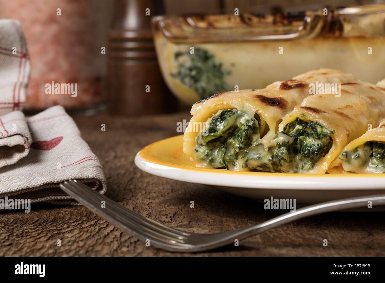 Eine gelbe Platte glutenfreier Cannelloni mit Spinat und Hüttenkäse. Stockfoto