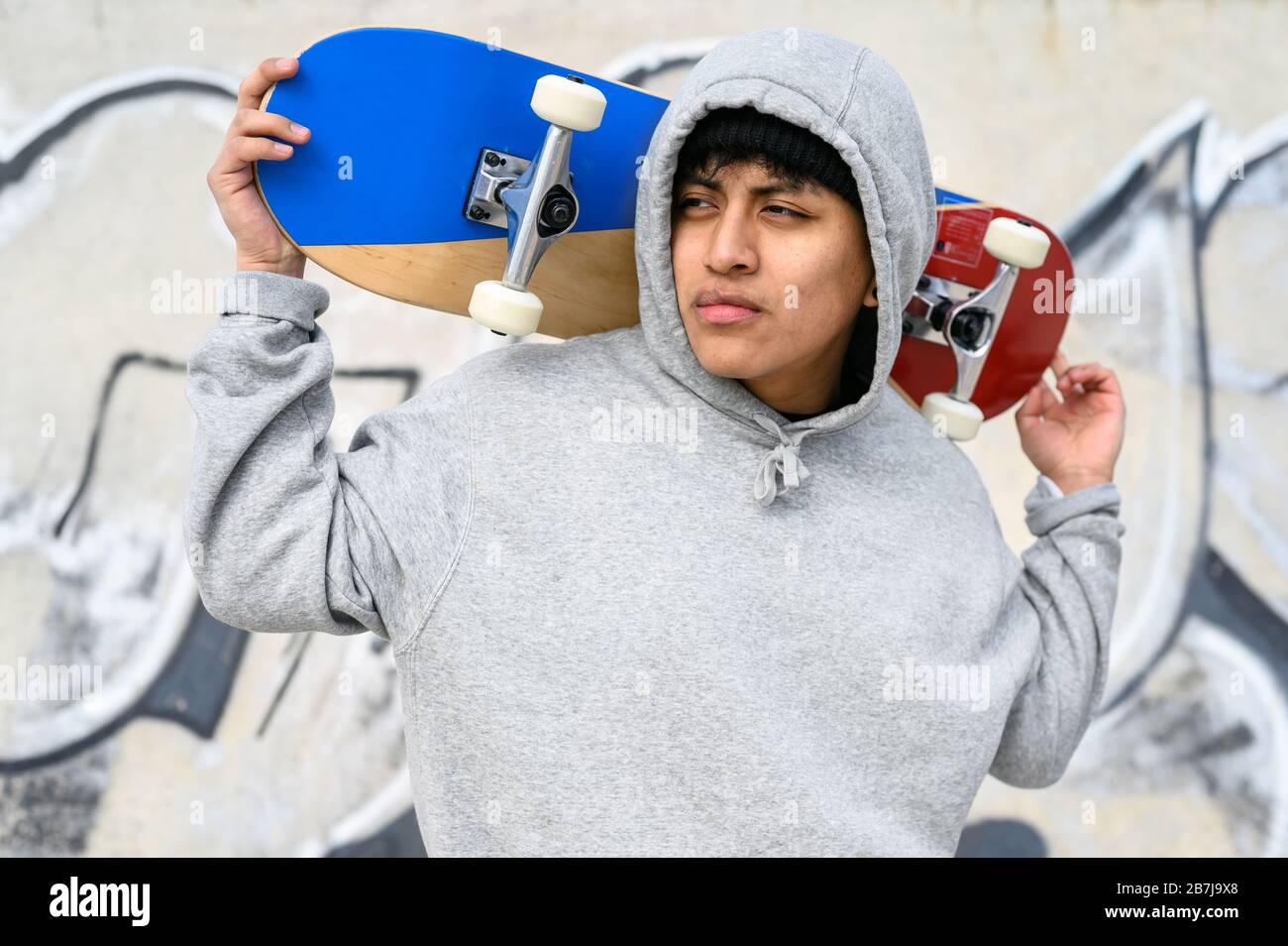 Junger lateinischer Skater-Mann posiert mit Skateboard im Skatepark. Stockfoto