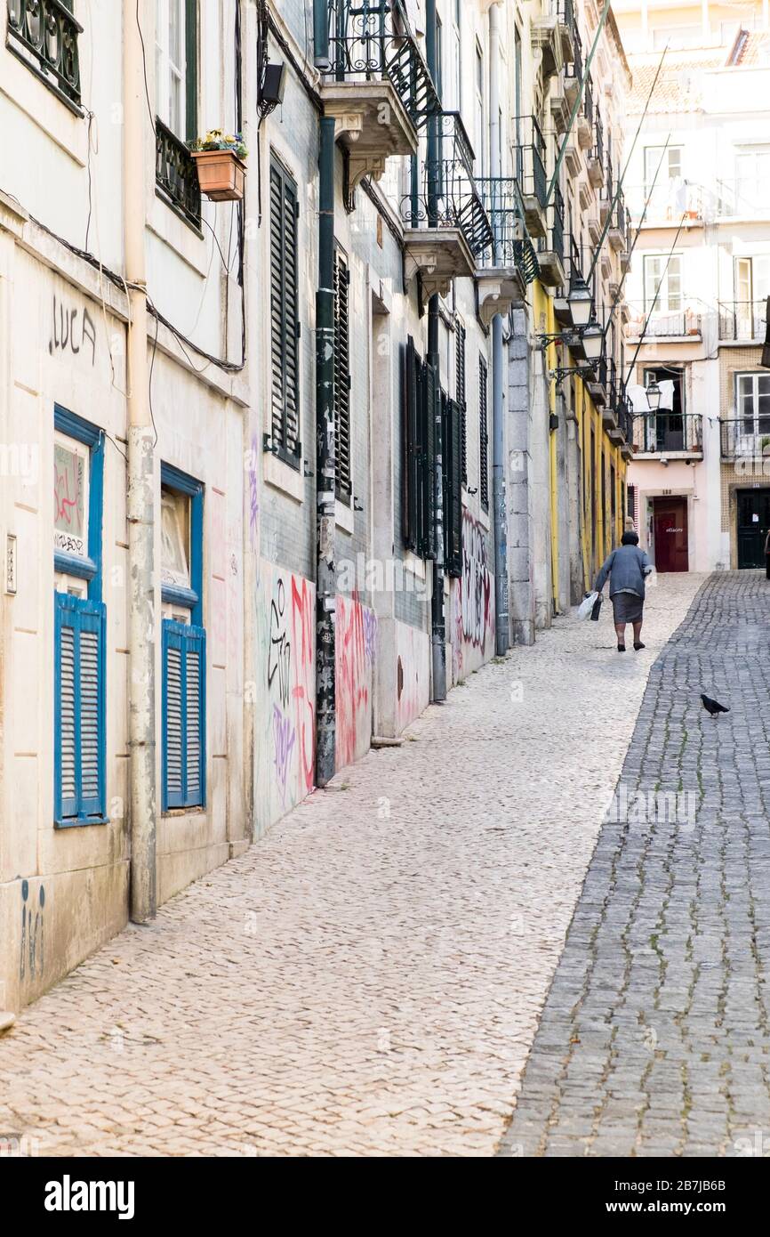 Ältere portugiesische Frau, die eine steile Kopfsteinpflasterstraße im Bairro Alto-Viertel in Lissabon, Portugal, hinaufgeht Stockfoto