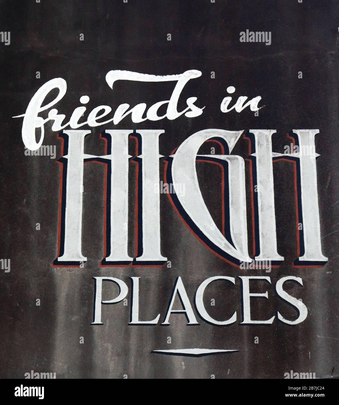 "Freunde an den höchsten Orten". Verwittertes altes Schild, das an der Seite eines Gebäudes in Auckland CBD, Neuseeland gemalt wurde Stockfoto