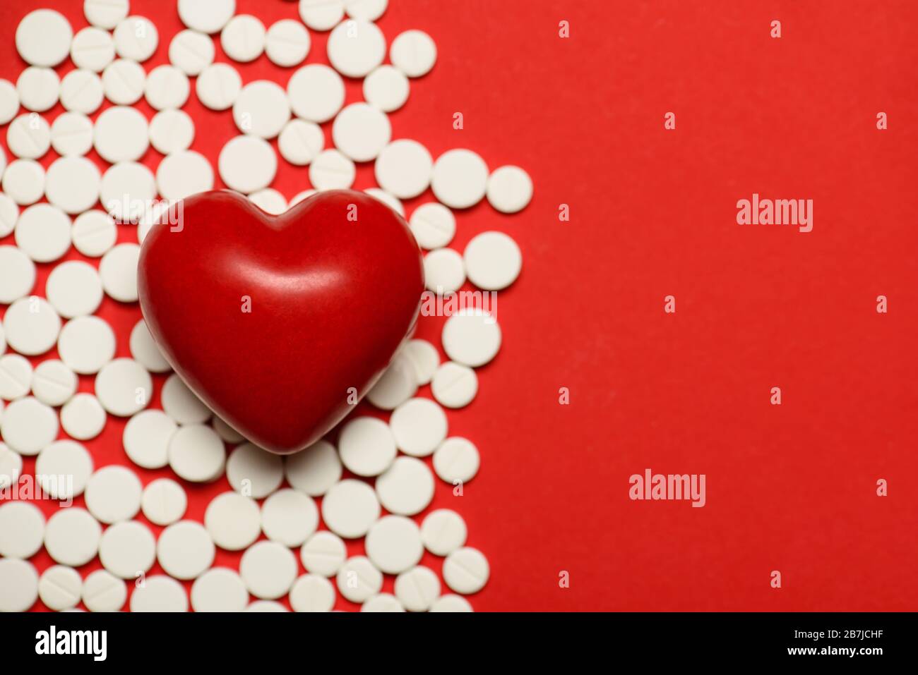 Zugeschnittenes Nahaufnahme des kleinen Herzens, das auf dem Hintergrund liegt, mit runden kleinen Pillen, kopieren Sie leeren Leerraum Stockfoto