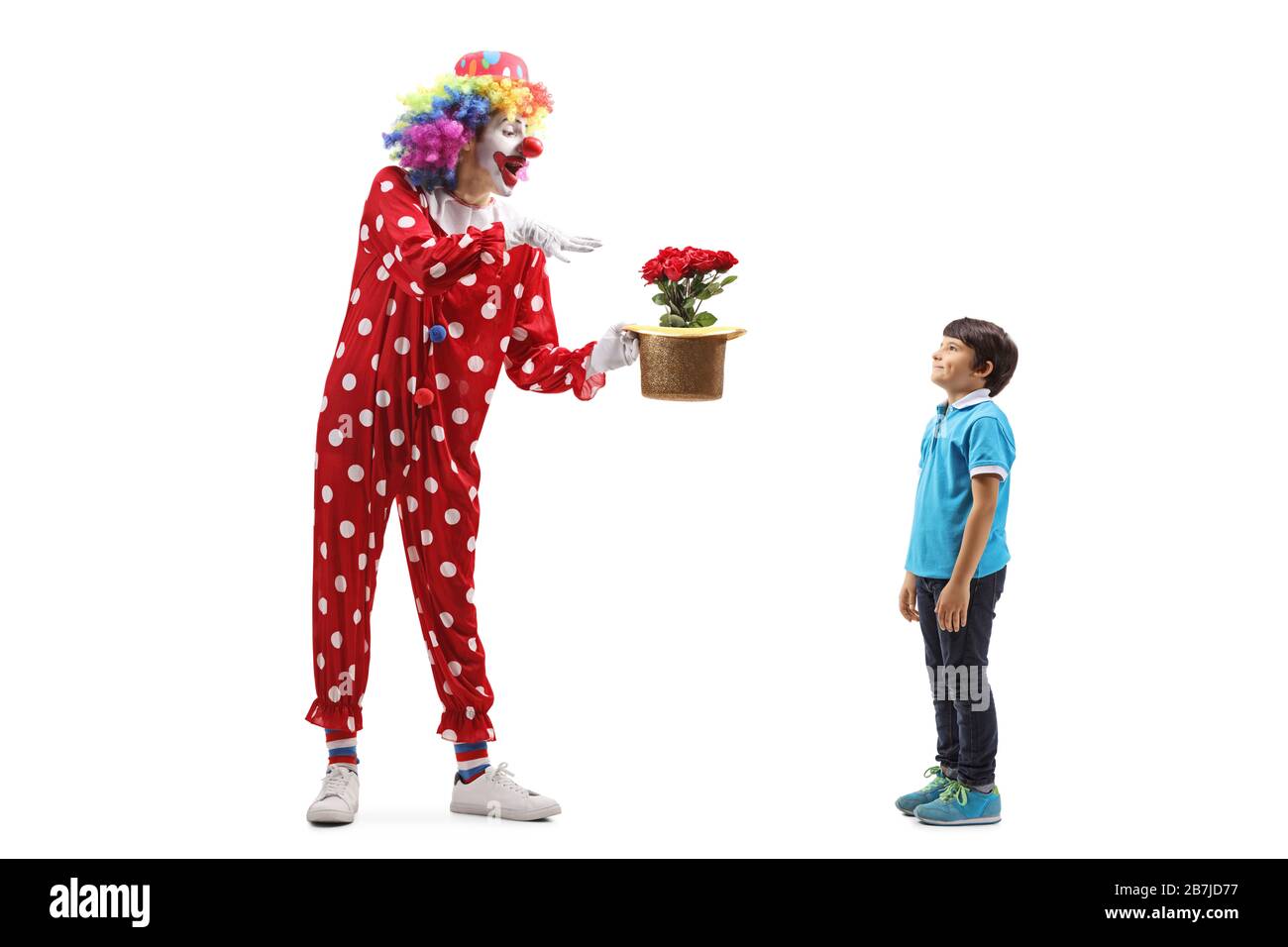 Lange Aufnahme eines Clowns, der einen Trick mit Blumen und Hut vor einem Jungen ausführt, der auf weißem Hintergrund isoliert ist Stockfoto