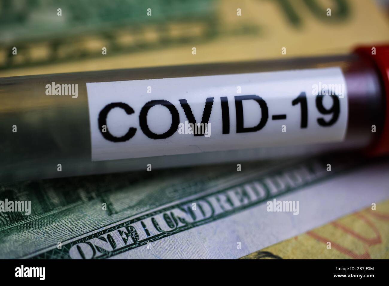 Corona-Virus-Kovid-19 Unsichere Folgekosten Konzeptsymbol: Makro-Nahaufnahme der isolierten Blutprobe Fläschchen auf 100-US-Dollar-Papier-Banknote Stockfoto