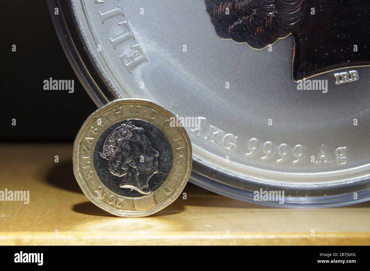 Große 1-KG-Silbermünze neben Pfund Sterling Concept Symbol Währung Investition fiat Währung sinkender Wert Rückgang Finanzkrise Rezession Stockfoto