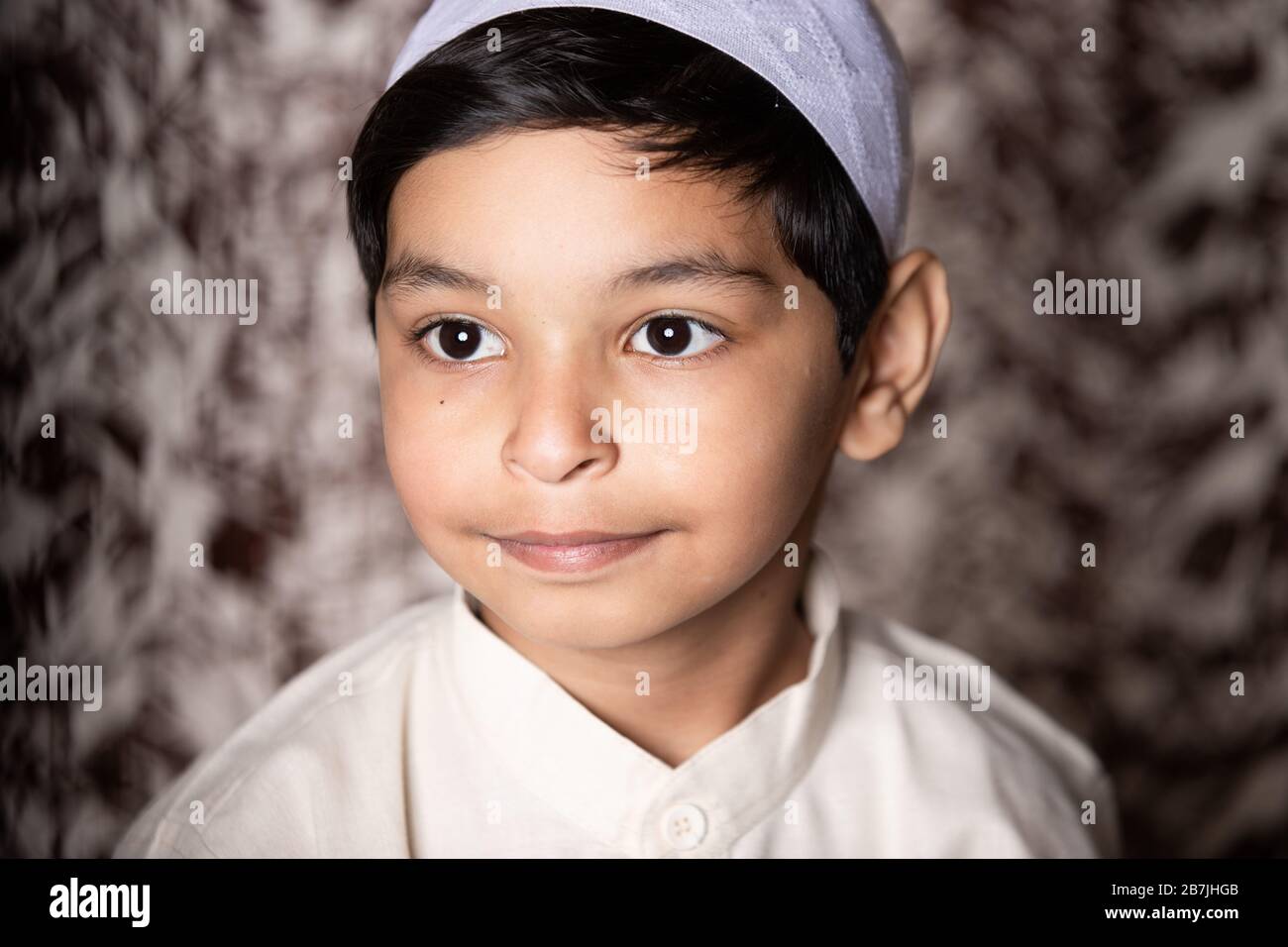 Muslim Child Portrait mit muslimischer Mütze und weißem Ethno-Kleid, das dem Licht Ausdruck gibt Stockfoto