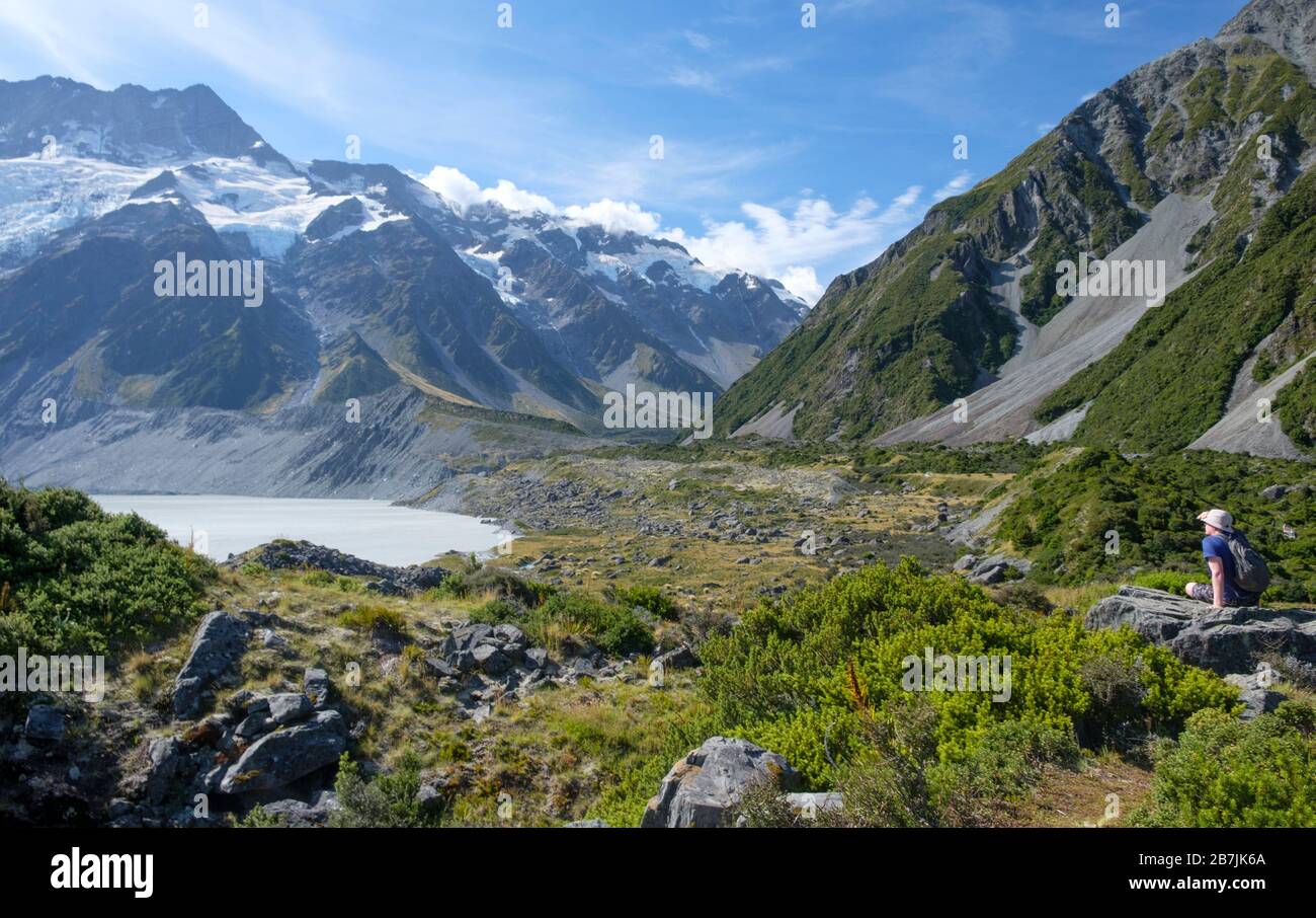 Man on Rock mit Gletschern und schneebedeckten Bergen und See, Aoraki/Mount Cook National Park, South Island, Neuseeland Stockfoto