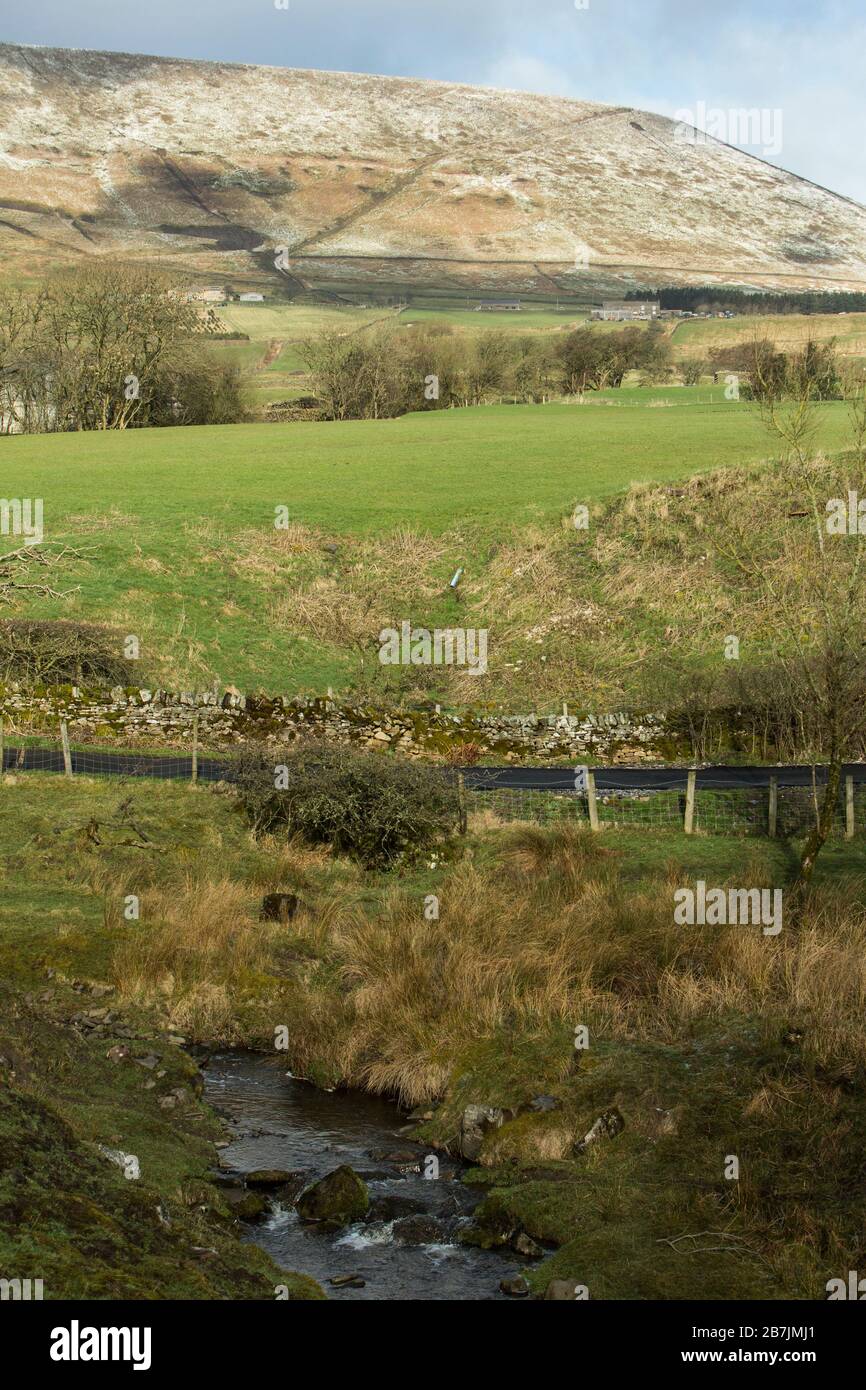 Schneebedeckter Pendle Hill im Winter mit dunklen Wolken und Sonnenschein, Lancashire, England, Großbritannien Stockfoto