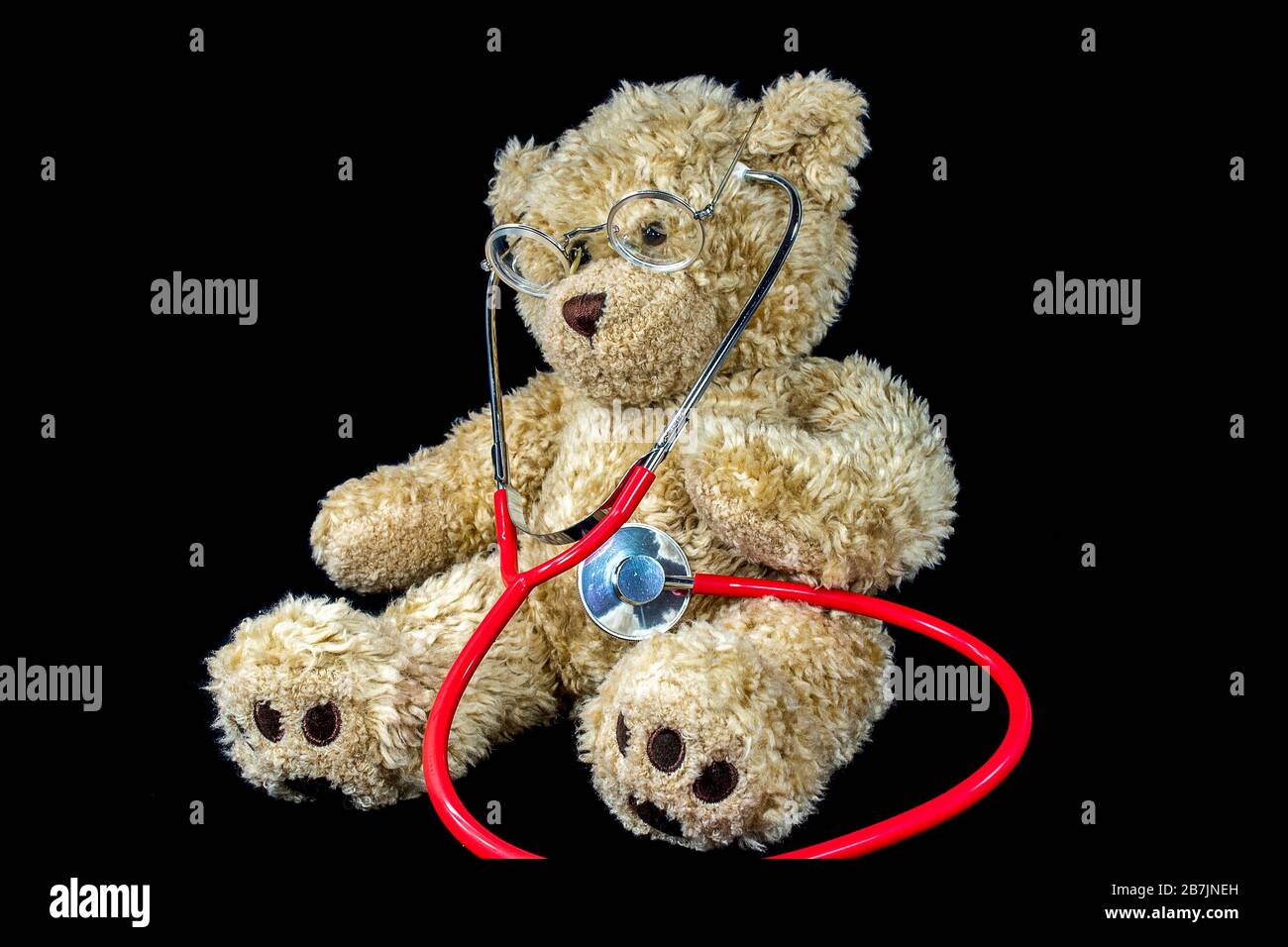 Brauner unscharfer Teddybär mit medizinischem Stethoskop auf Schwarz Stockfoto