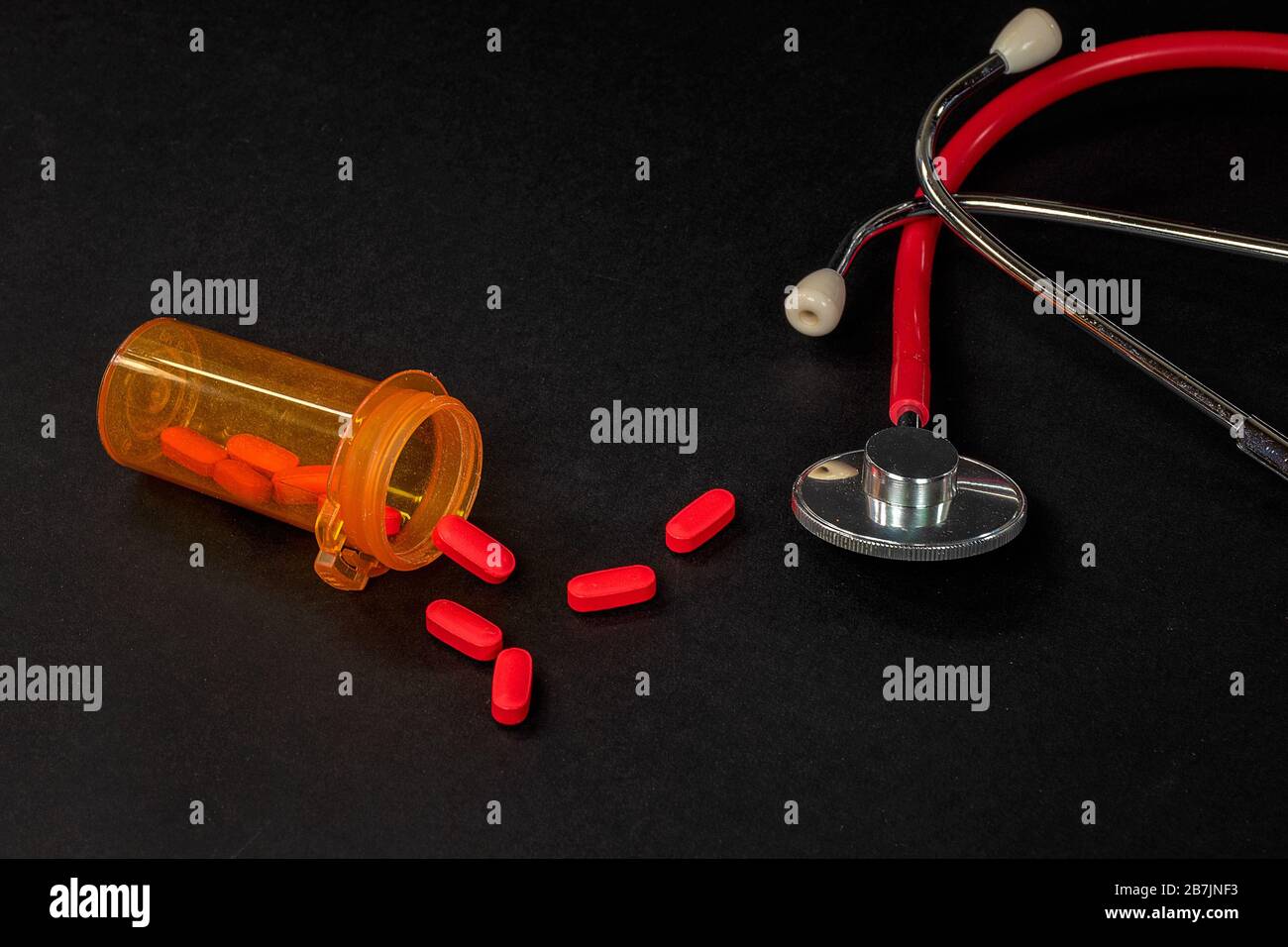 Rote Pillen in oranger Rezeptflasche mit medizinischem Stethoskop Stockfoto