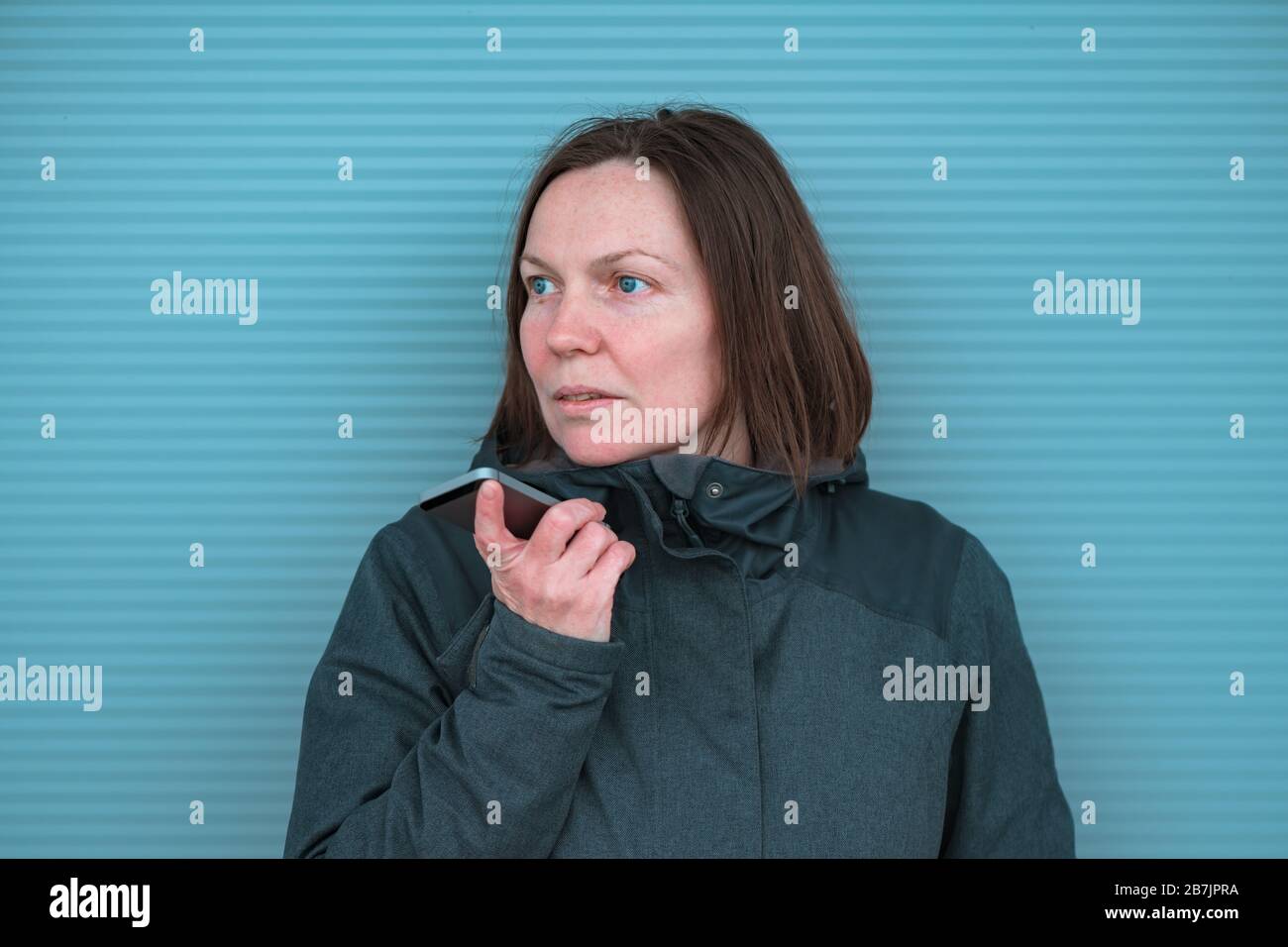 Lässige Frau, die mit dem Handy unterwegs auf der Straße in der modernen urbanen Umgebung kommuniziert, selektive Fokussierung Stockfoto