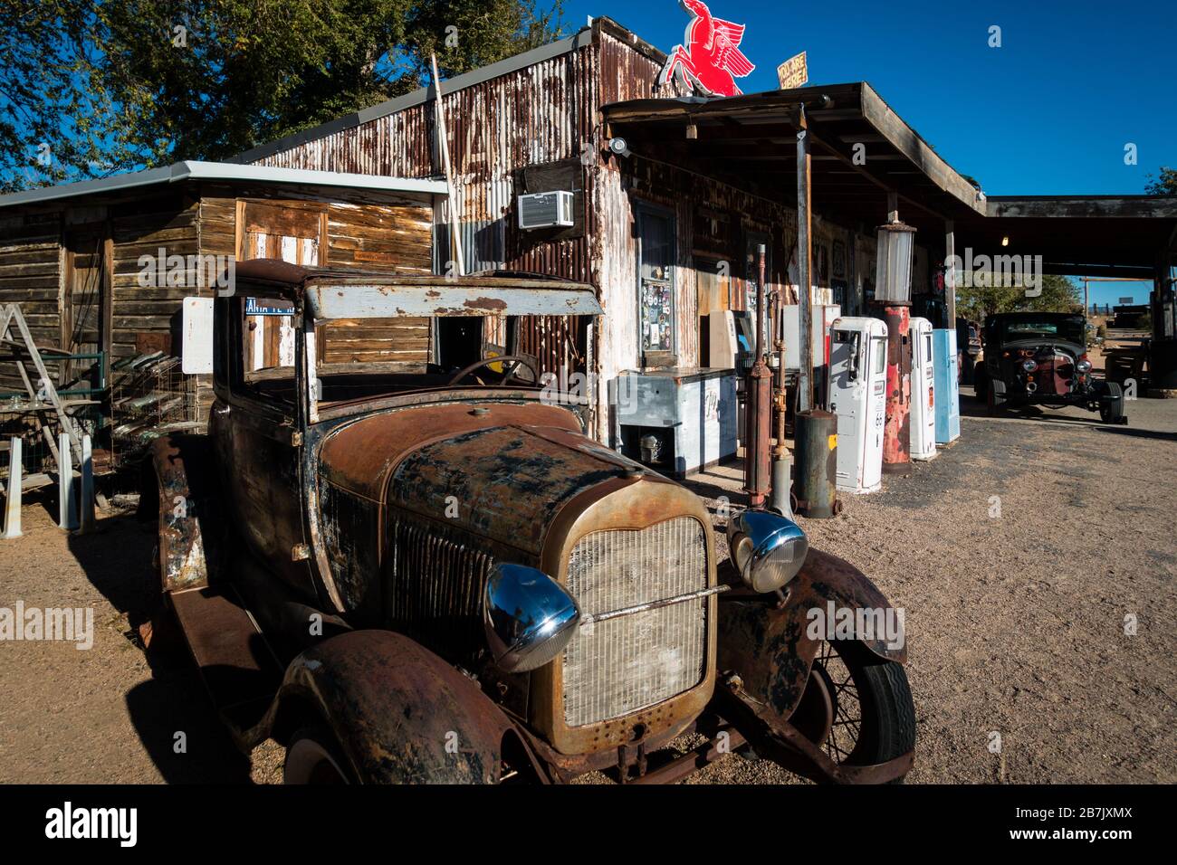 Verrosttes altes Auto, das vor der historischen, verschlechterten Tankstelle an der Route 66 in der Nähe von Seligman, Arizona steht. Sonniges Tageslicht, keine Menschen sichtbar. Stockfoto