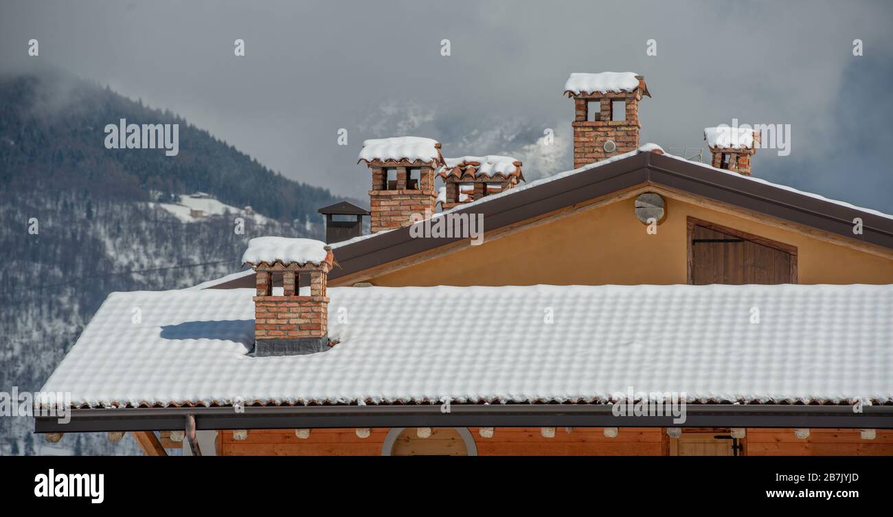 Schneebedecktes Dach mit Kamin Stockfoto
