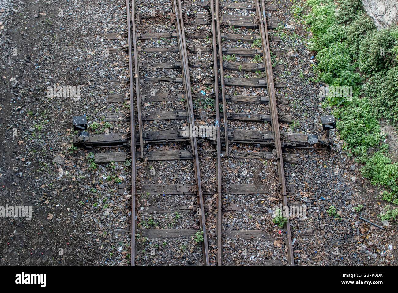 Altes Eisenbahnfoto von oben aufgenommen die Schiene fährt von unten nach oben fort. Es wurden Kieselsteine und Gras herumgeführt. Fotografiert auf einem Stockfoto