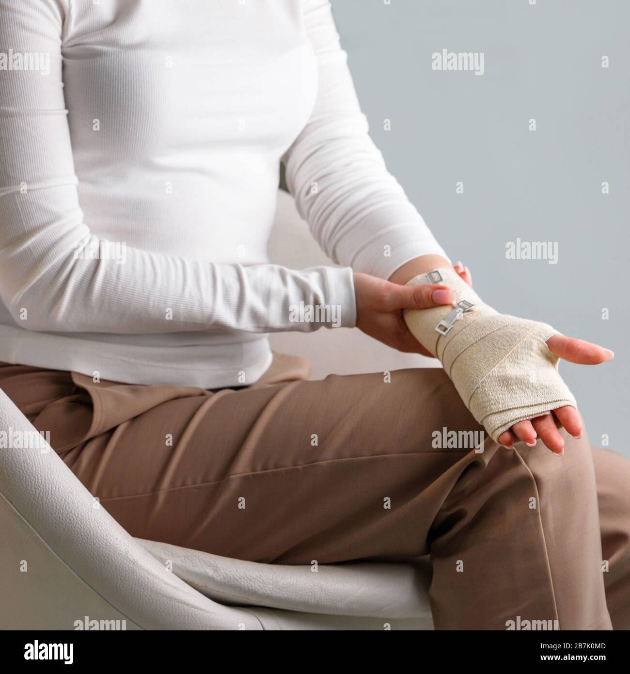 Frau, die ihr gewickeltes schmerzhaftes Handgelenk mit einem flexiblen elastischen, unterstützenden orthopädischen Verband berührt, nachdem sie Sport oder Verletzung nicht erfolgreich war, Nahaufnahme. Carpal tun Stockfoto