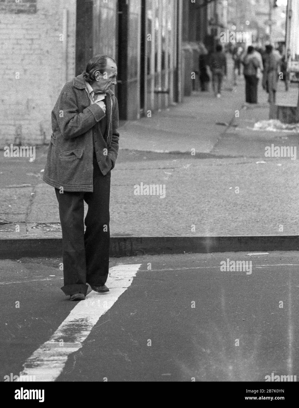Juli 1970 Schwarz-Weiß-Filmbild des Obdachlosen, der zurückblickt, als er die Straße auf der Lower East Side, New York City, überquert. Stockfoto