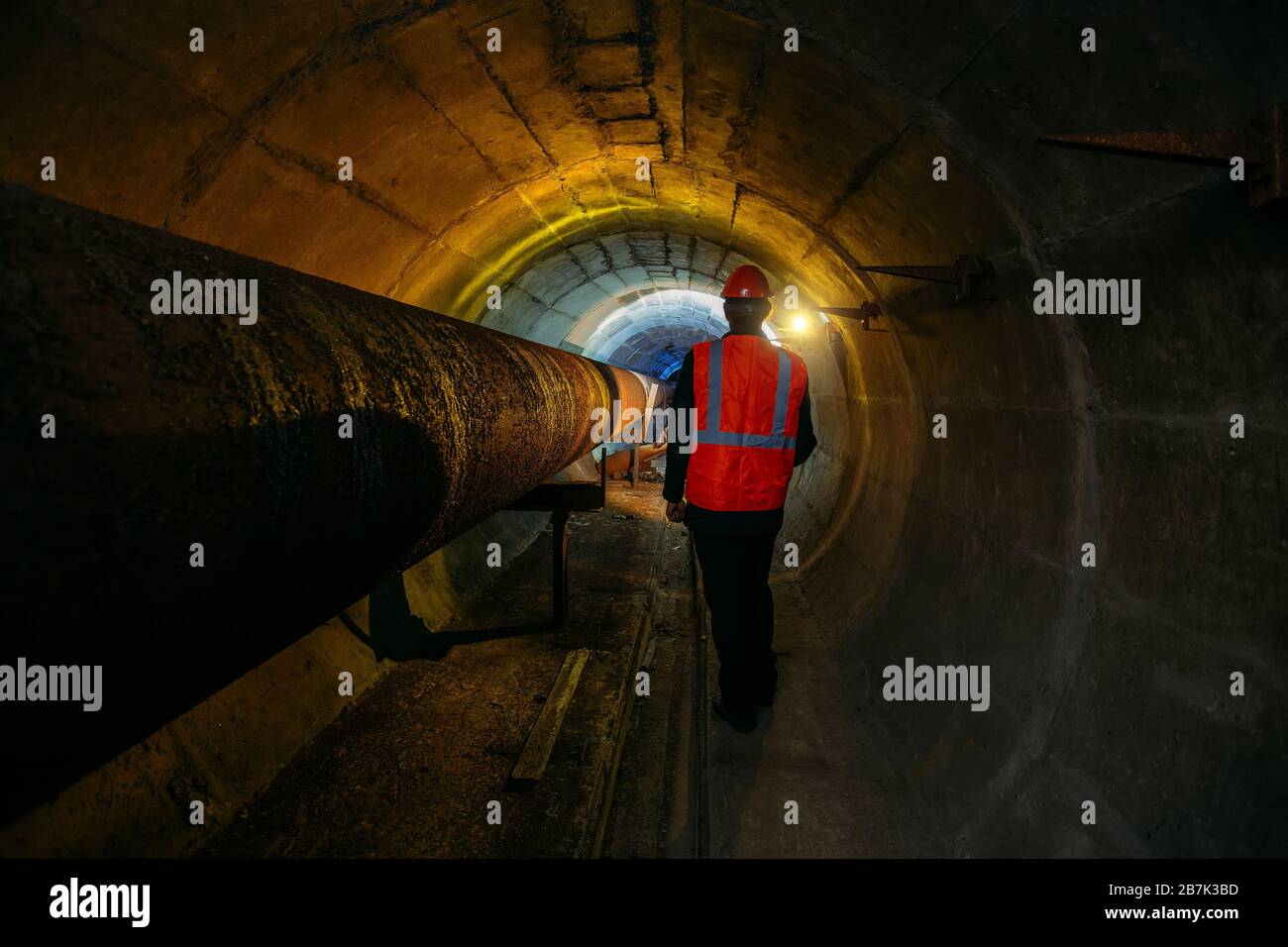 Tunnelarbeiter untersuchen Pipeline im unterirdischen Tunnel Stockfoto