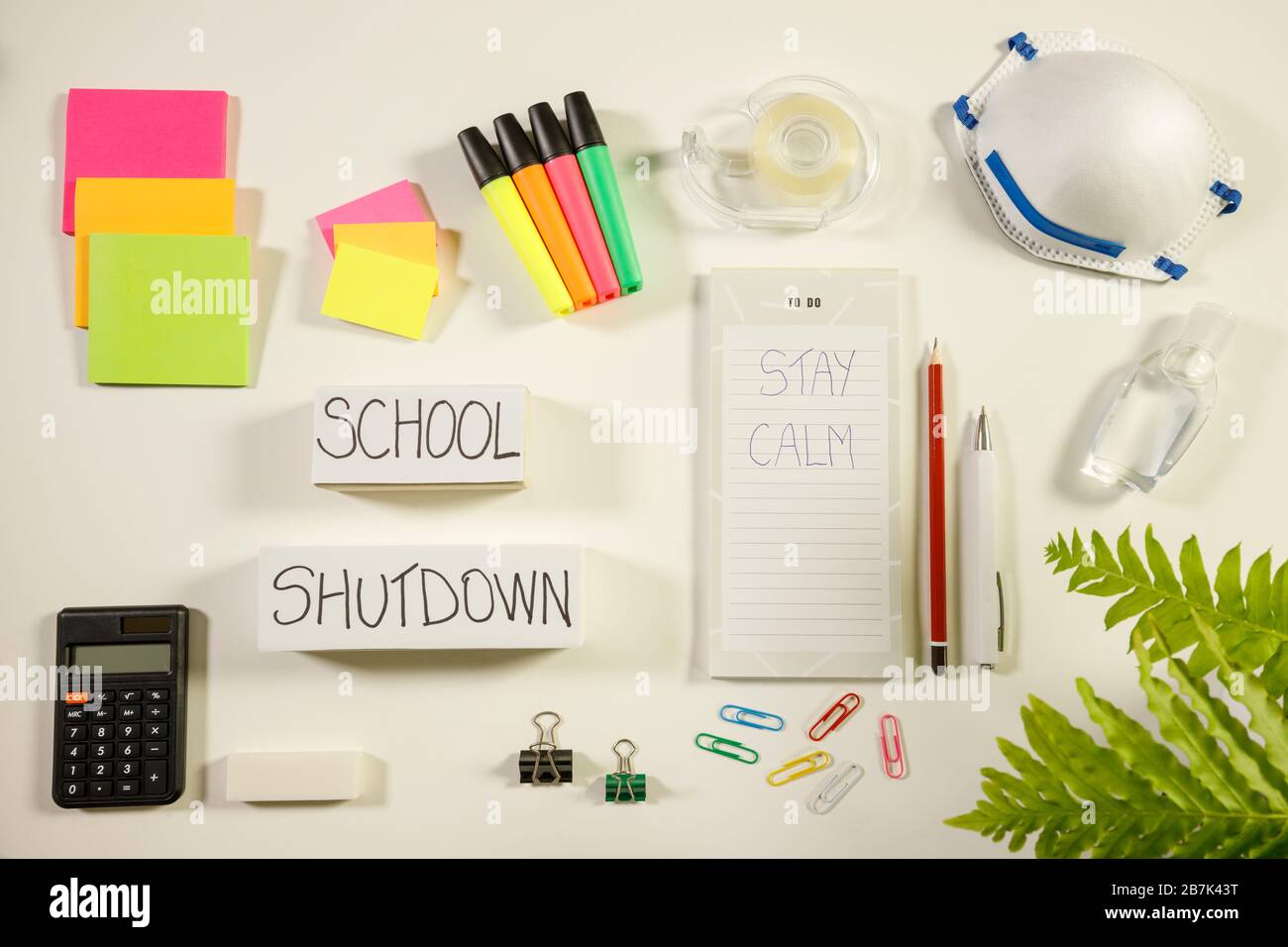 Caronavirus Schulabschaltung Konzept mit persönlicher Maske, Händededesinfektionsmittel und Schreibwaren auf weißem Flachlay, ruhig auf Notizblock, Overhead-Ansicht geschrieben Stockfoto
