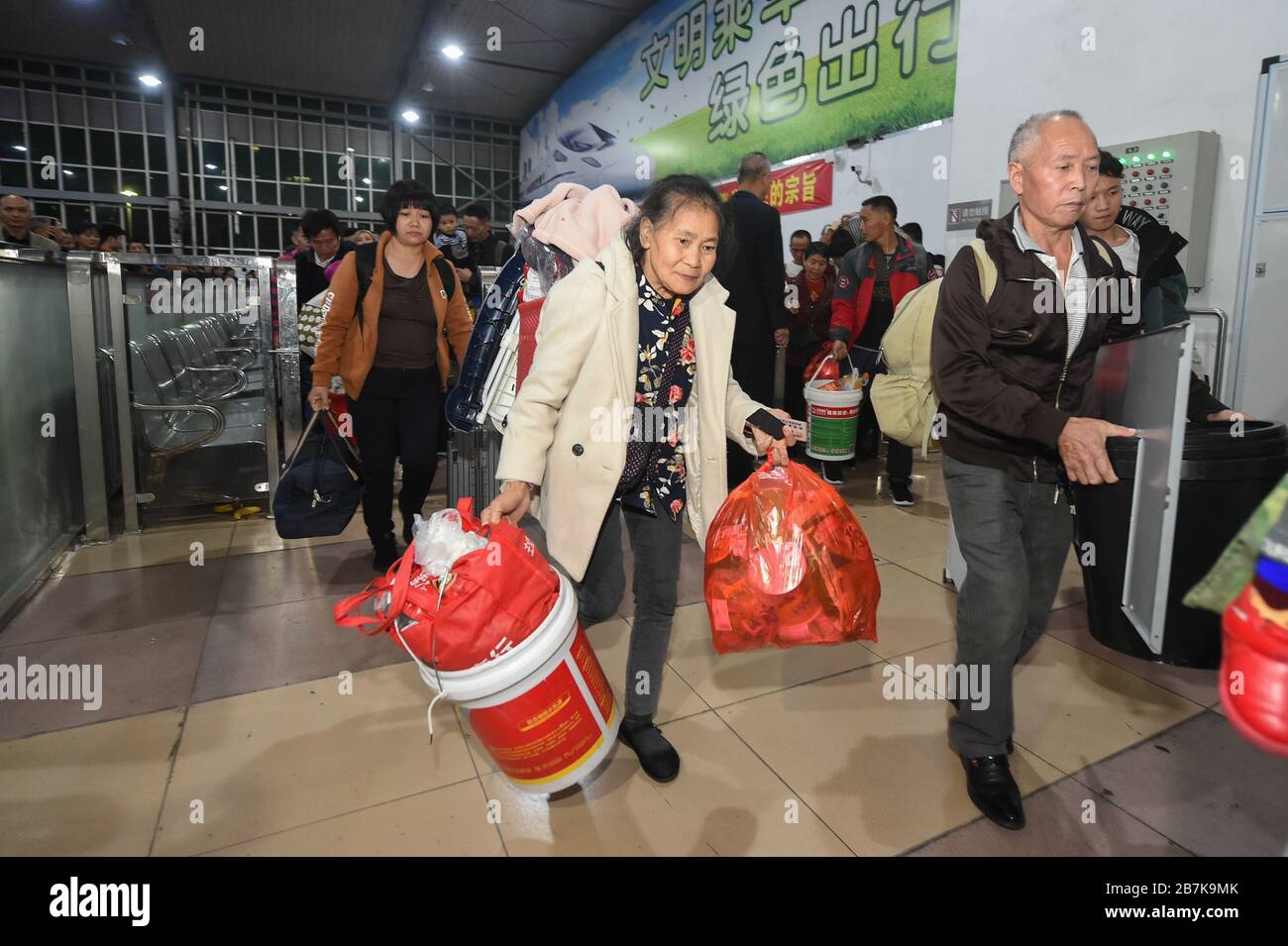 Die Passagiere tragen einen Plastikeimer, der ihr Gepäck enthält, und bereiten sich darauf vor, an Bord des Zuges zu gehen, der zu Hause am Bahnhof Shenzhen, der Stadt Shenzhen, liegt Stockfoto