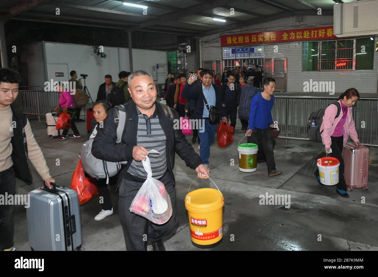 Die Passagiere tragen einen Plastikeimer, der ihr Gepäck enthält, und bereiten sich darauf vor, an Bord des Zuges zu gehen, der zu Hause am Bahnhof Shenzhen, der Stadt Shenzhen, liegt Stockfoto