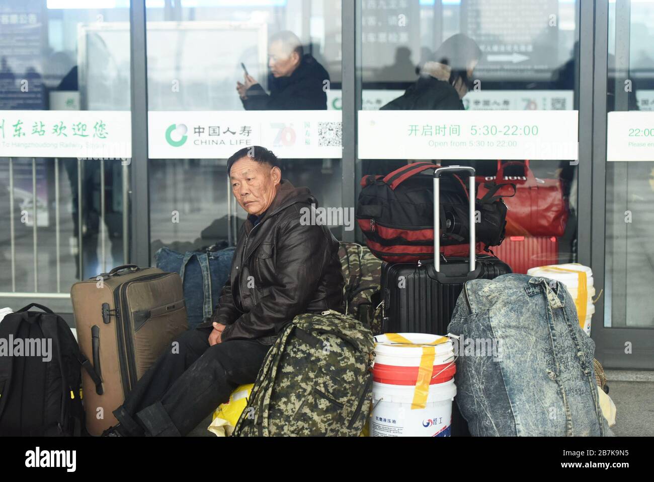 Die Passagiere tragen einen Plastikeimer, der ihr Gepäck enthält, und bereiten sich darauf vor, an Bord des Zuges zu gehen, der zu Hause am Bahnhof Hangzhoudong, Hangzhou Cit, fährt Stockfoto